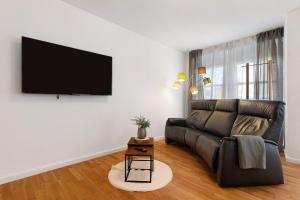 a living room with a black leather couch and a flat screen tv at Ferienwohnung Merlin in Ettenheim