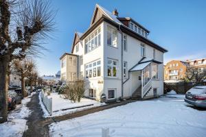 a white house with snow on the street at Haus Übersee Wohnung Sansibar in Travemünde