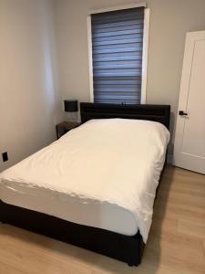 a bedroom with a bed with white sheets and a window at The Millertime Experience in Brantford +17 photos