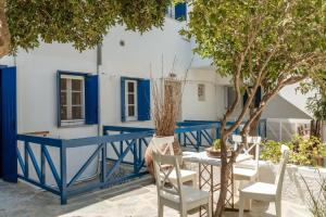 a blue and white house with a table and chairs at Waterfront Masterpiece in Tinos