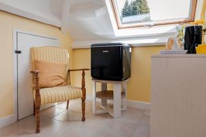 a tv and a chair in a room at Le Verger Chambres d'hotes in Ségur-le-Château