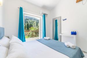a bedroom with a large window with blue curtains at Doliva Studio John private jacuzzi in Agios Gordios