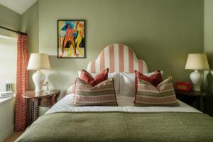 a bedroom with a bed with a striped headboard and pillows at The Queen's Head in Broad Chalke