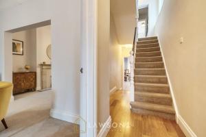 a staircase in a home with white walls and wooden floors at Fit for a King-size Nap I Parking in Windsor