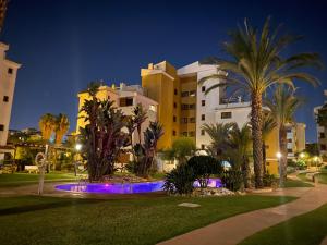 a building with palm trees in front of a resort at Spacious ground floor apartment in Punta Prima