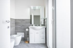 a white bathroom with a sink and a mirror at Casa Andrea in Assemini +15 photos