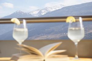 two glasses of water and a book on a table with mountains at Waalhof Ferienwohnung Mohnblume in Silandro +17 photos