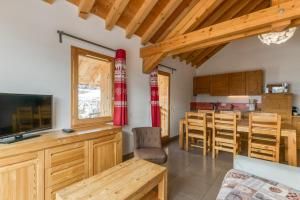 a living room with a television and a table and chairs at Chalet Arvina in Saint-Jean-dʼArves