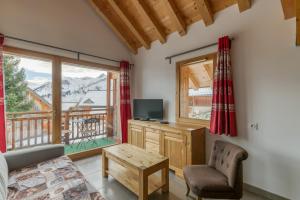 a living room with a bed and a tv and a window at Chalet Arvina in Saint-Jean-dʼArves