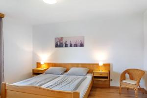 a bedroom with a bed with two night stands and a chair at Ferienwohnungen Hackerhof in Bad Füssing