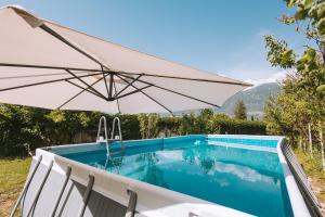 a white umbrella sitting next to a swimming pool at Matscherhof Lana in Lana