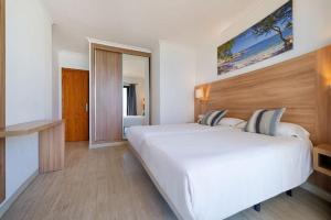 a bedroom with a large white bed and a mirror at R2 Cala Millor in Cala Millor