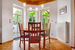 a dining room with a table and chairs and windows at Inge Huus in Hude