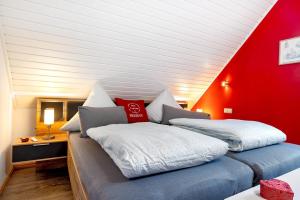 two beds in a room with a red wall at Inge Huus in Hude