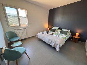 a bedroom with a bed and two chairs and a window at Villa Lucia in Narbonne