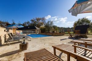 a patio with two benches and a swimming pool at Le Moulin in Guizengeard