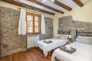 two beds in a room with a stone wall at Casa Pirinea in Belsierre
