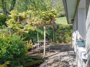 a patio with a table and chairs under a tree at Maison de vacances Camille in Artigues