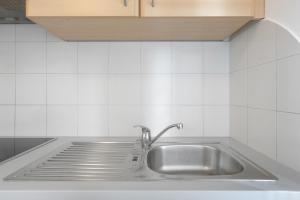 a stainless steel sink in a white tiled kitchen at Georgshof - Eppan in Appiano sulla Strada del Vino +97 photos