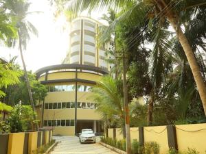 a car parked in front of a building with palm trees at Krishna vykundam guruvayur in Guruvāyūr