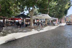 a cobblestone street with people sitting at tables and umbrellas at Casa Canopa in Setúbal