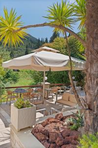 a patio with an umbrella and chairs and palm trees at Doliva Studio Anthi private jacuzzi in Agios Gordios