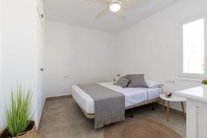 a white bedroom with a bed and a window at Chalet a 150m de la playa y piscina privada in Cala en Bosc +17 photos