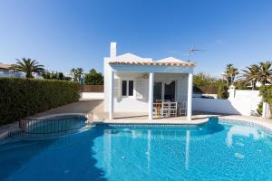 a villa with a swimming pool and a house at Chalet a 150m de la playa y piscina privada in Cala en Bosc