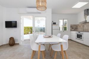 a white dining room with a white table and chairs at Chalet a 150m de la playa y piscina privada in Cala en Bosc