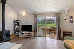 a living room with a tv and a sliding glass door at La Cense De La Mérelie - Le Logis in Saint-Geniès
