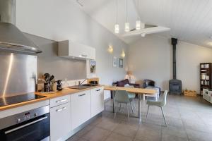 a kitchen with white cabinets and a table with chairs at La Cense De La Mérelie - Le Logis in Saint-Geniès