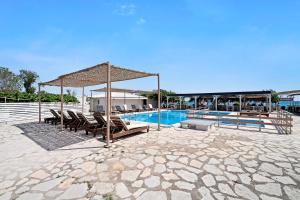 a swimming pool with lounge chairs and a pavilion at Iguana studio 16 in Preveza