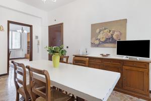 a dining room with a white table and a tv at Casa Grace - Casa al Mare in Vado Ligure