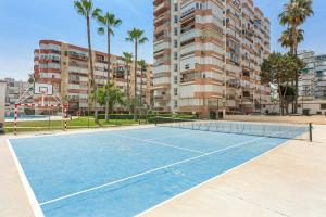 a tennis court in front of a building with palm trees at Plazamar 044 in Torre del Mar