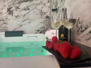 a table with two glasses of white wine and strawberries at BEDBLUESKY-Sparklingsuite nel centro di Dolceacqua in Dolceacqua