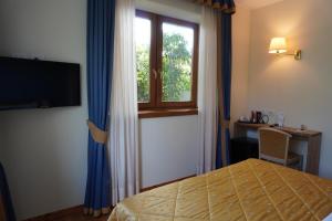 a bedroom with a bed and a window and a desk at Giorgio e Flora Ristorante e Locanda in Arsiero