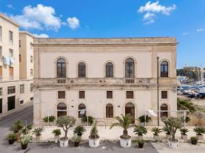 an old building with palm trees in front of it at La Finestra sul Mare di Ortigia Suite Luxury in Syracuse