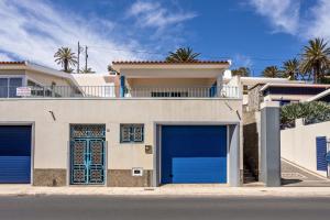 a house with two blue garage doors on a street at Formosa Beach in Porto Santo