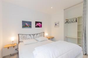 a white bedroom with a white bed and two lamps at Le Pequelet in Payzac