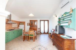 a kitchen with green cabinets and a table with a tv at Appartamento Melissa a Orosei in Orosei +12 photos