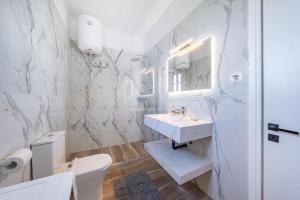 a white bathroom with a sink and a toilet at Kassiopi Apartment 2 in Kassiopi