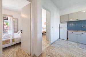 a white kitchen with a bed and a refrigerator at Kassiopi Apartment 2 in Kassiopi