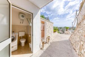 a bathroom with a toilet next to a stone wall at Villa Liscedde Leuca in Castrignano del Capo +45 photos