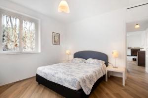 a white bedroom with a bed and two windows at Villa Angelina in Lavagna