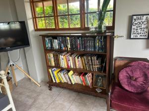 a book shelf filled with books next to a tv at Mariri Farm Cottage in Patentie