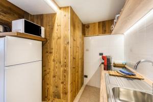 a kitchen with wooden walls and a refrigerator at Il Nido di Letizia in Châtillon