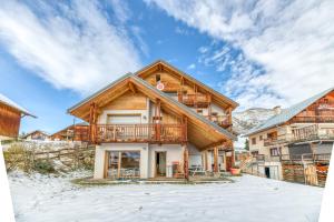 a log home with a deck in the snow at Chalet Arvina in Saint-Jean-dʼArves
