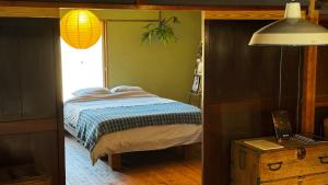 ein Schlafzimmer mit einem Bett, einem Fenster und einer Lampe in der Unterkunft MEKIKI古民家 yorimichi in Yamanashi