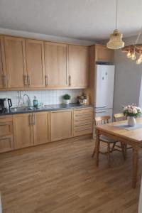 a kitchen with wooden cabinets and a table and a refrigerator at Maria Isabelles boende nr 3 in Fjugesta