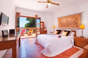 a bedroom with a bed and a desk and a balcony at Villa Juan Carlos in Cala Vinyes +30 photos